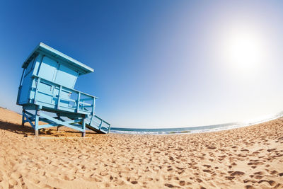 Lifeguard hut on beach against clear blue sky