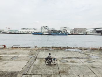 High angle view of man riding bicycle on walkway against river at harbor