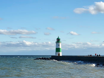 Lighthouse by sea against sky