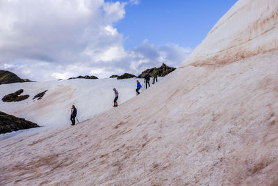 People walking on mountain against sky