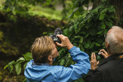 Rear view of man photographing with smart phone outdoors