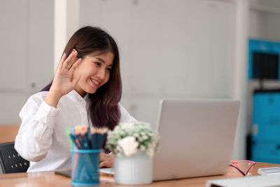 Young woman using phone on table