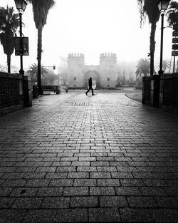 Rear view of man on footpath by street in city