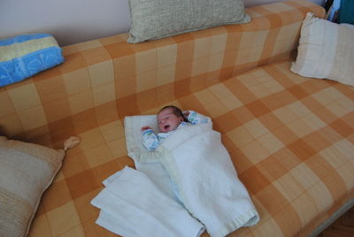 Close-up of cute baby lying on bed at home