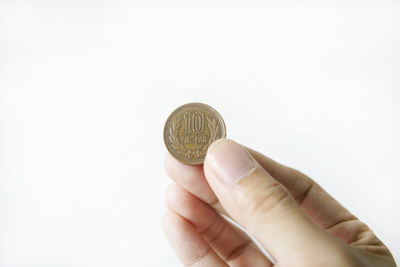 Close-up of hand holding coin against white background