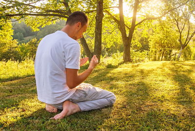 Side view of man sitting on field