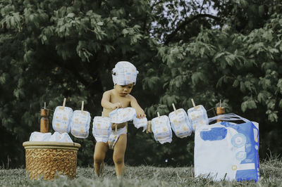 Shirtless boy drying diapers on land