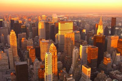 Modern buildings in city against sky during sunset