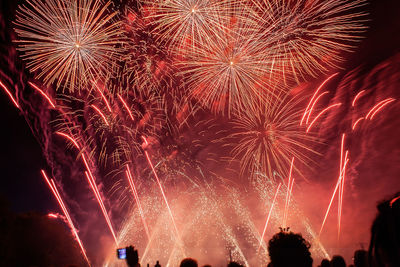 Silhouette people against firework display at night