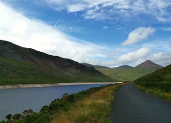 Scenic view of road by mountains against sky