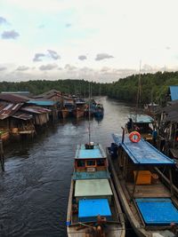Boats moored in sea by houses against sky