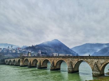 Arch bridge over river against sky