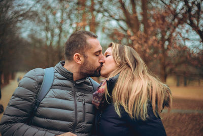 Young couple kissing while standing on field