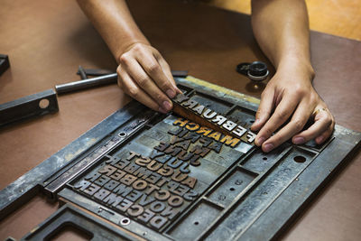 Cropped image of hands fixing letterpress on workbench at workshop