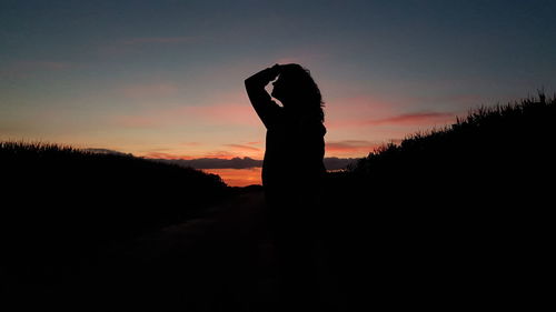 Silhouette person standing against orange sky