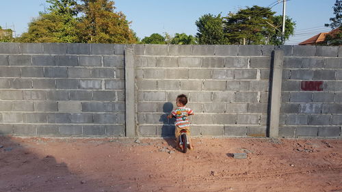 Full length of boy riding bicycle against wall