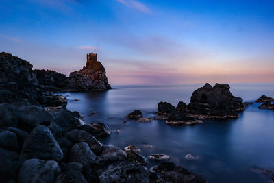 Scenic view of rocks in sea against sky during sunset