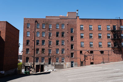 Road by buildings against clear sky in city