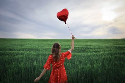 Rear view of woman standing on field against sky
