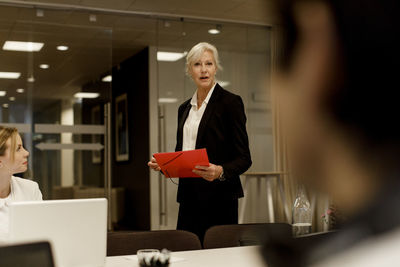 Businesswoman discussing with male and female colleagues in meeting at workplace