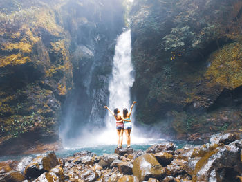 Man standing on rock looking at waterfall