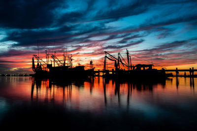 Two shrimp boats tied to a pier at sunset