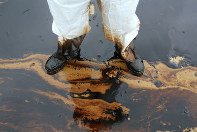 Low section of person standing on wet footpath