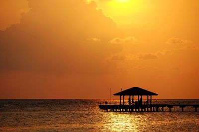 Silhouette built structure on sea against sky during sunset