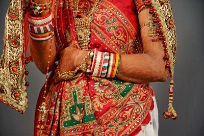 Midsection of bride in traditional clothing over gray background