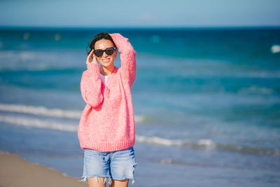 Portrait of young woman standing at beach
