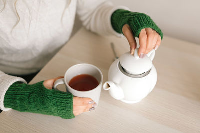 High angle view of hand holding tea cup on table