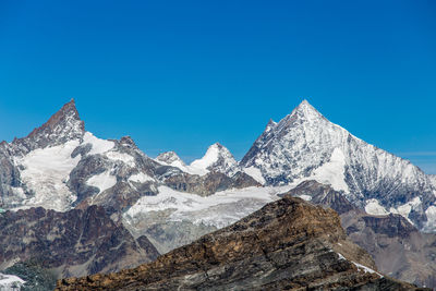 Scenic view of snowcapped mountains against clear blue sky