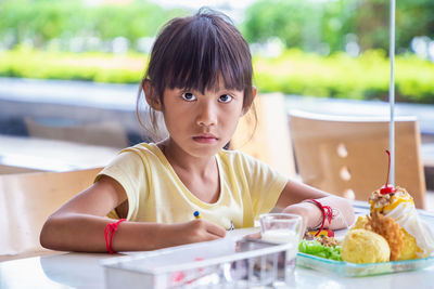 Portrait of woman sitting with ice cream on table