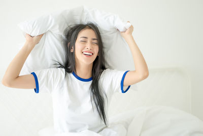 Smiling young woman lying on bed at home