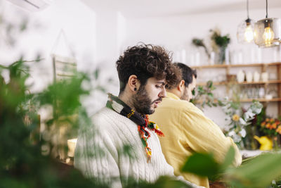 Florists working by colleague at flower shop