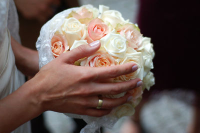Cropped image of bride holding rose flower bouquet at wedding