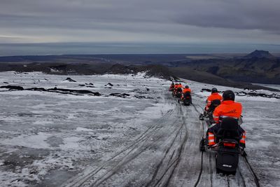 Rear view of people snowmobiling during winter