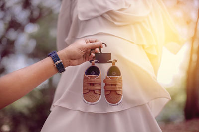 Cropped hand of man holding baby booties by pregnant woman 