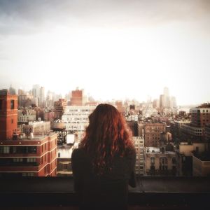 Rear view of woman standing against buildings in city