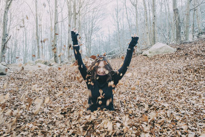 Woman enjoying autumn and catching falling yellow leaves