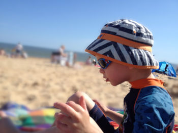 Midsection of boy on beach against sky