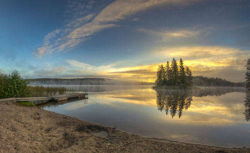 Scenic view of calm lake against cloudy sky