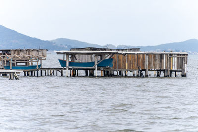 Stilt house by sea against clear sky