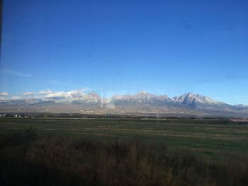 Scenic view of land and mountains against blue sky