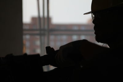 Close-up portrait of silhouette man holding window