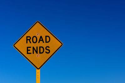 Road sign against clear blue sky