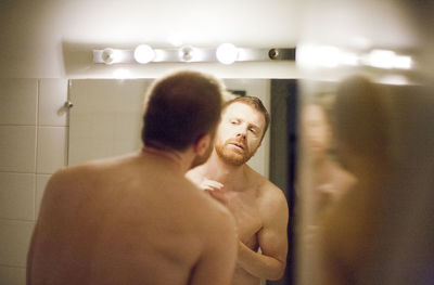 Rear view of shirtless man standing in bathroom