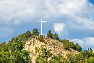 Low angle view of cross on mountain against sky