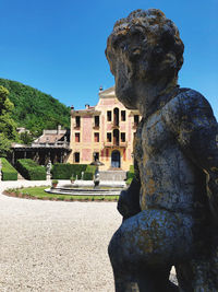 Statue by building against clear blue sky