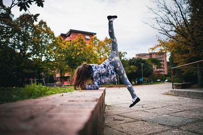 Full length of woman during gymnastic by building against sky